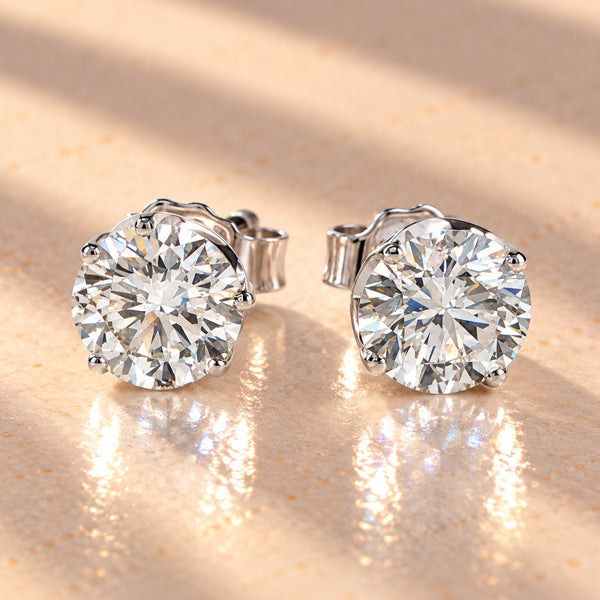 Round brilliant diamond stud earrings in white gold, featuring classic four-claw settings.