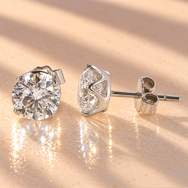 Round brilliant diamond stud earrings in white gold, showing four-claw settings, side profile, posts and butterfly backs.