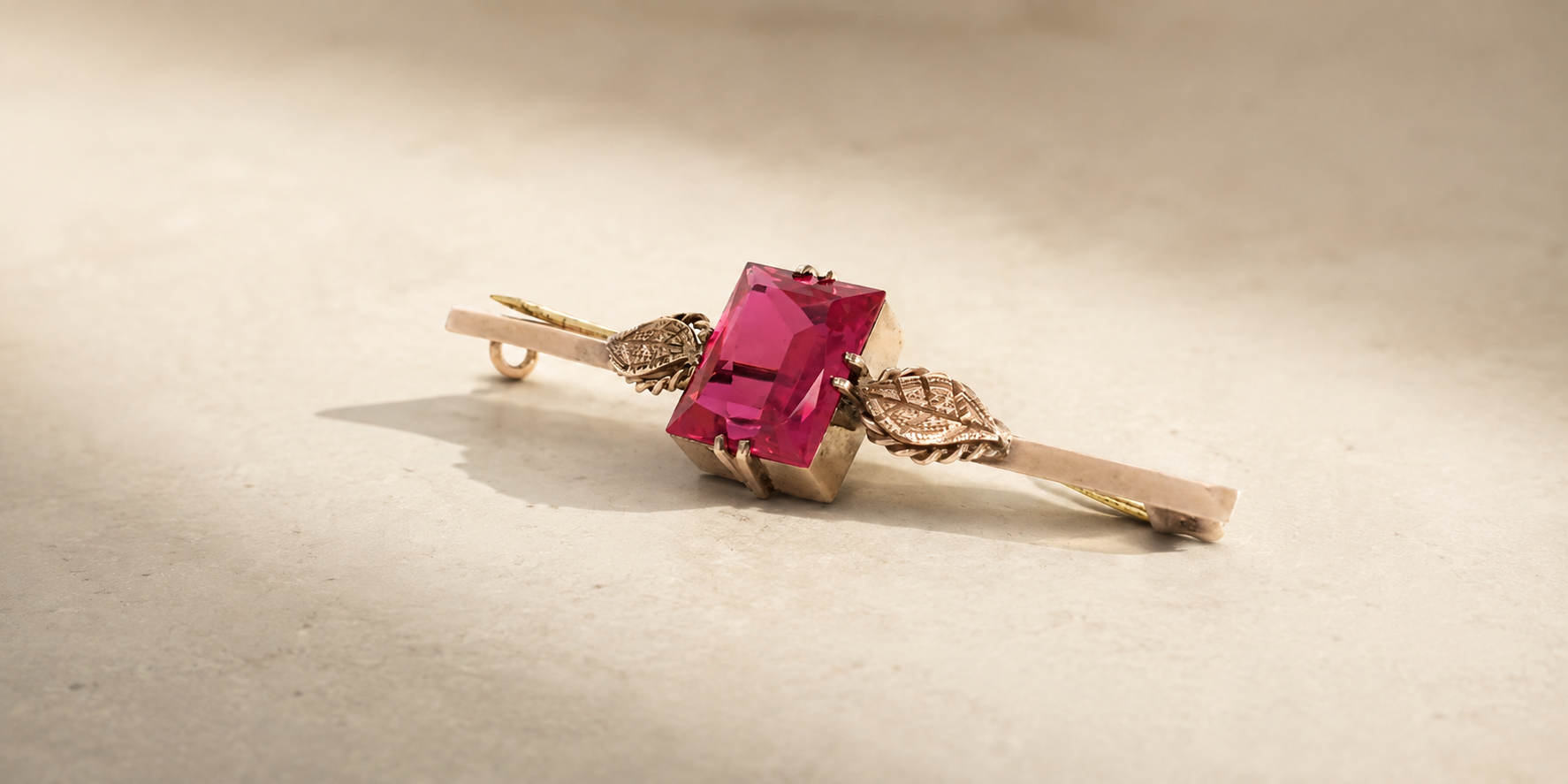 Vintage gold brooch with a pink coloured gemstone ready to be transformed through jewellery remodelling by Fishers Jewellers.