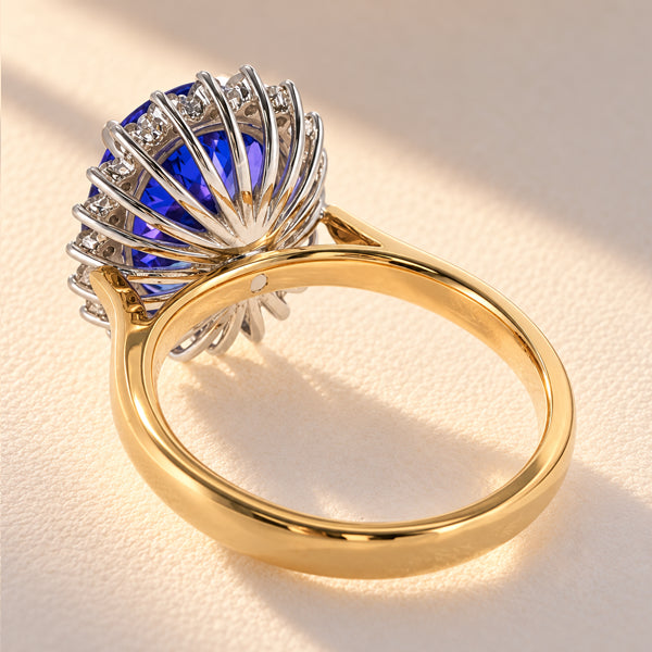 Rear three-quarter view of an 18ct yellow and white gold tanzanite diamond halo ring, showing the intricate openwork basket setting and polished gold shank.