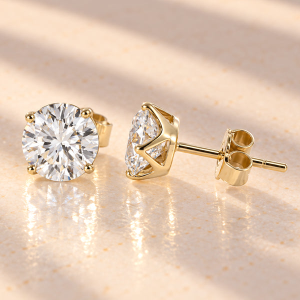 Round brilliant diamond stud earrings in yellow gold, showing four-claw settings, posts and butterfly backs.